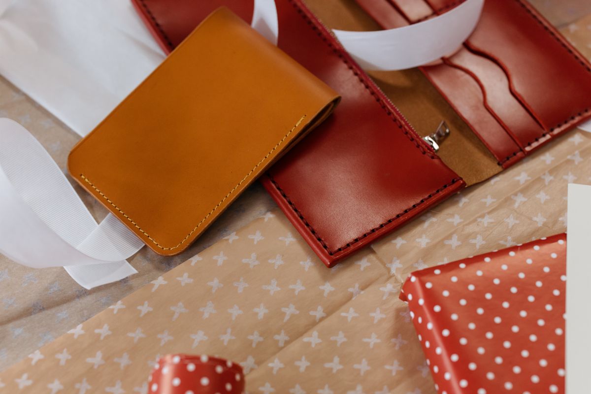 A tan leather wallet and a burgundy leather wallet lying on tissue paper