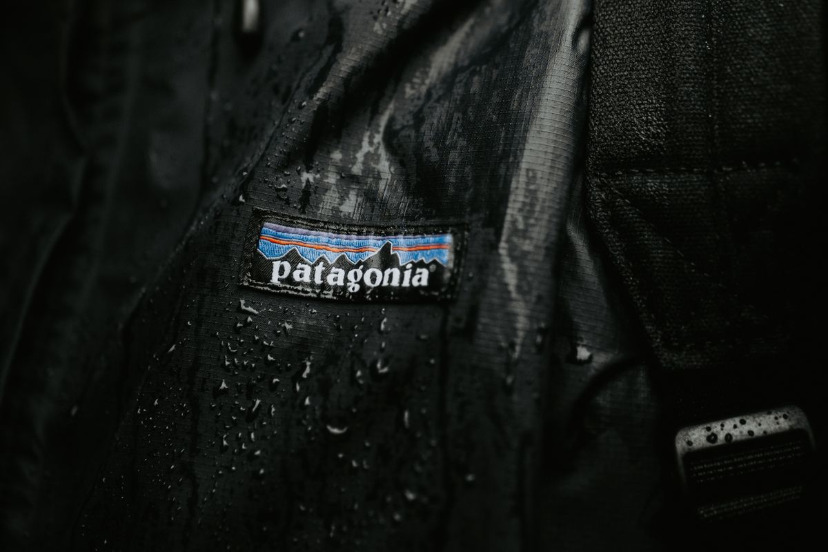 A folded waterproof shell jacket beside an open day bag