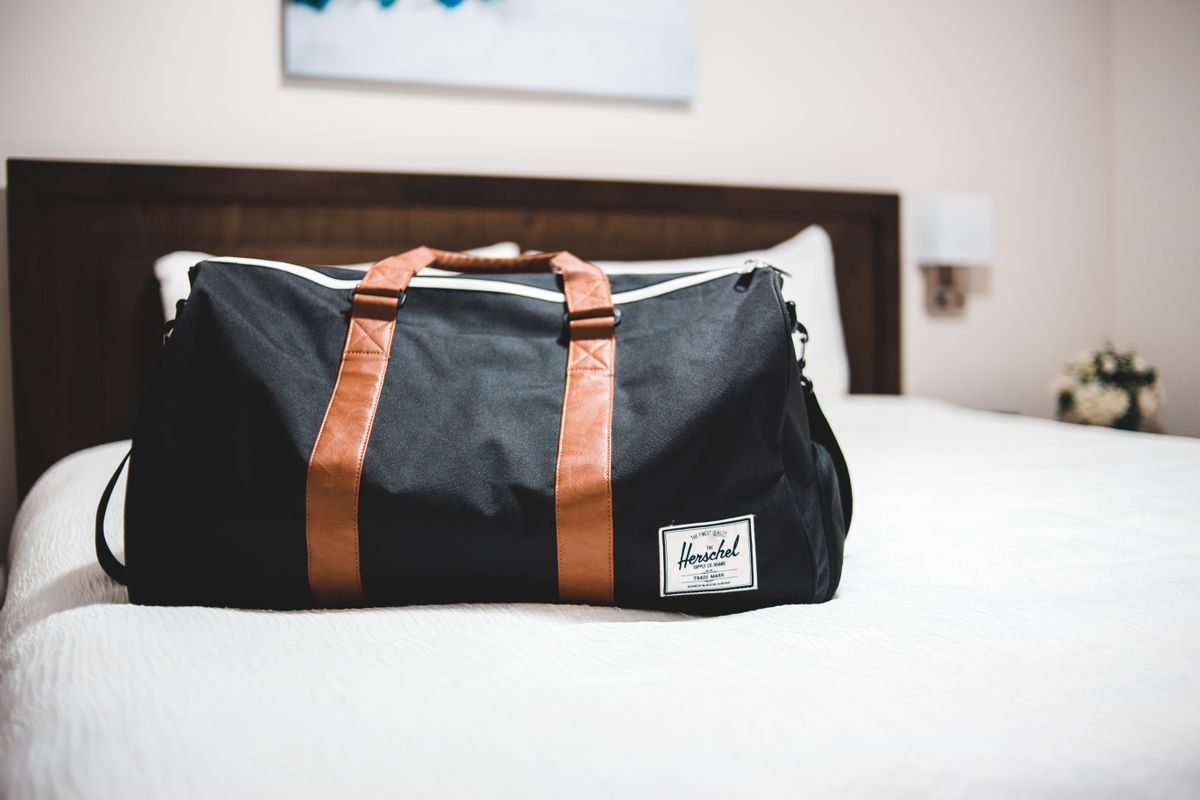 A sporty weekender bag lying on a hotel bed