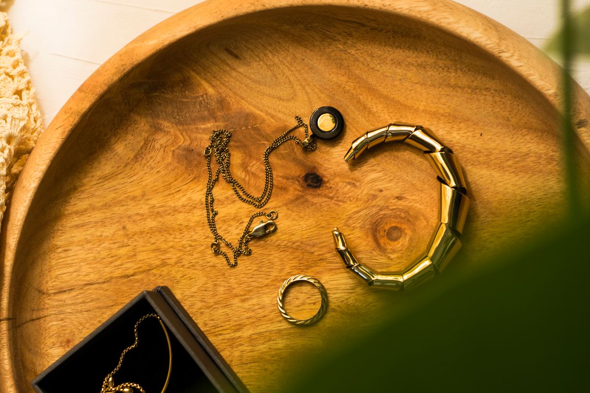 Gold-tone jewelry arranged on a round wooden tray