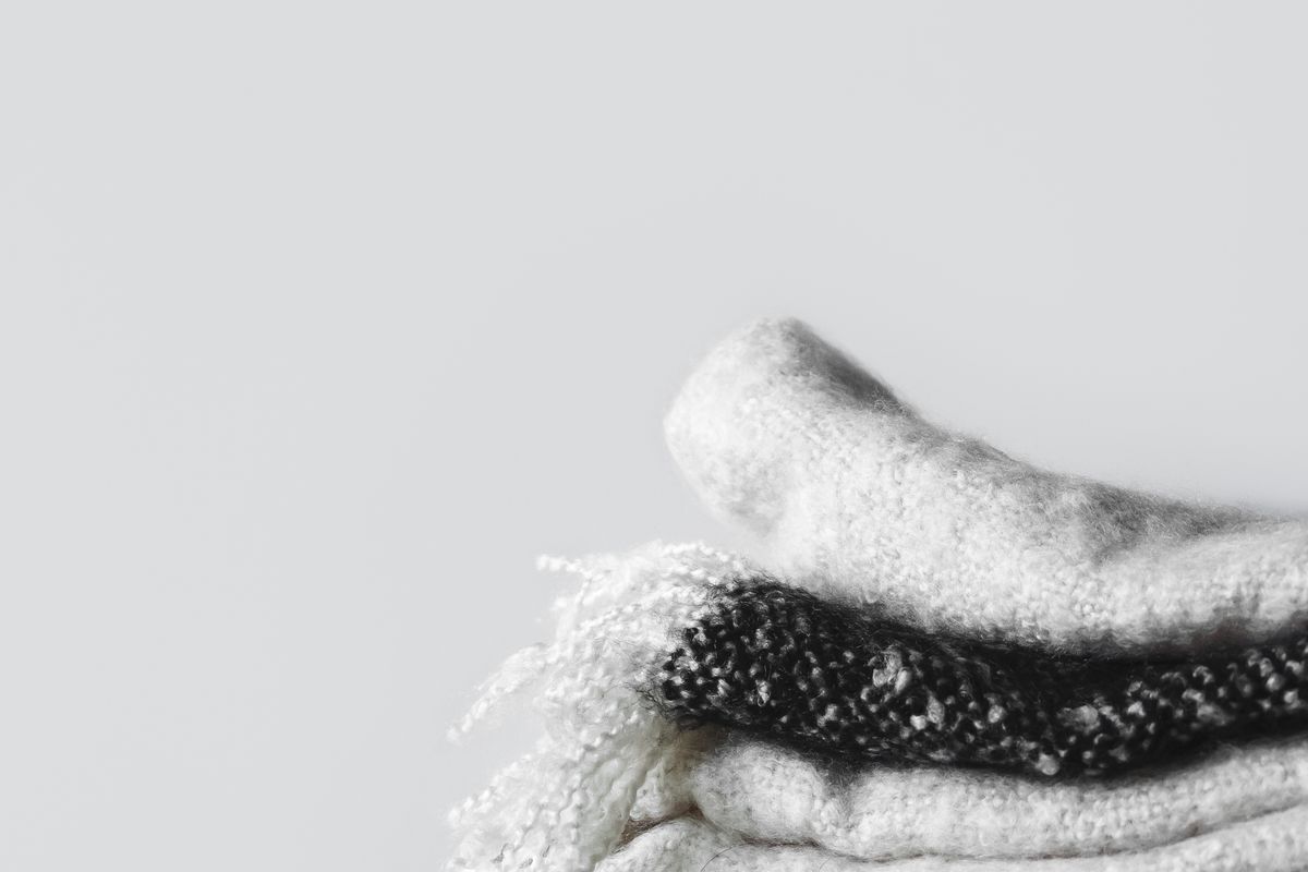 Folded white and black knit scarves with fringed edges
