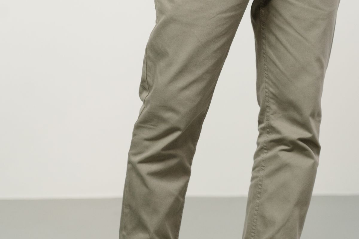 A close-up of a trouser hem resting against a shoe