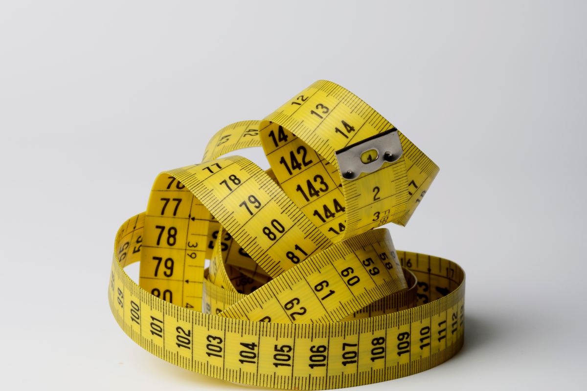 A row of identical garments on hangers with different size tags attached